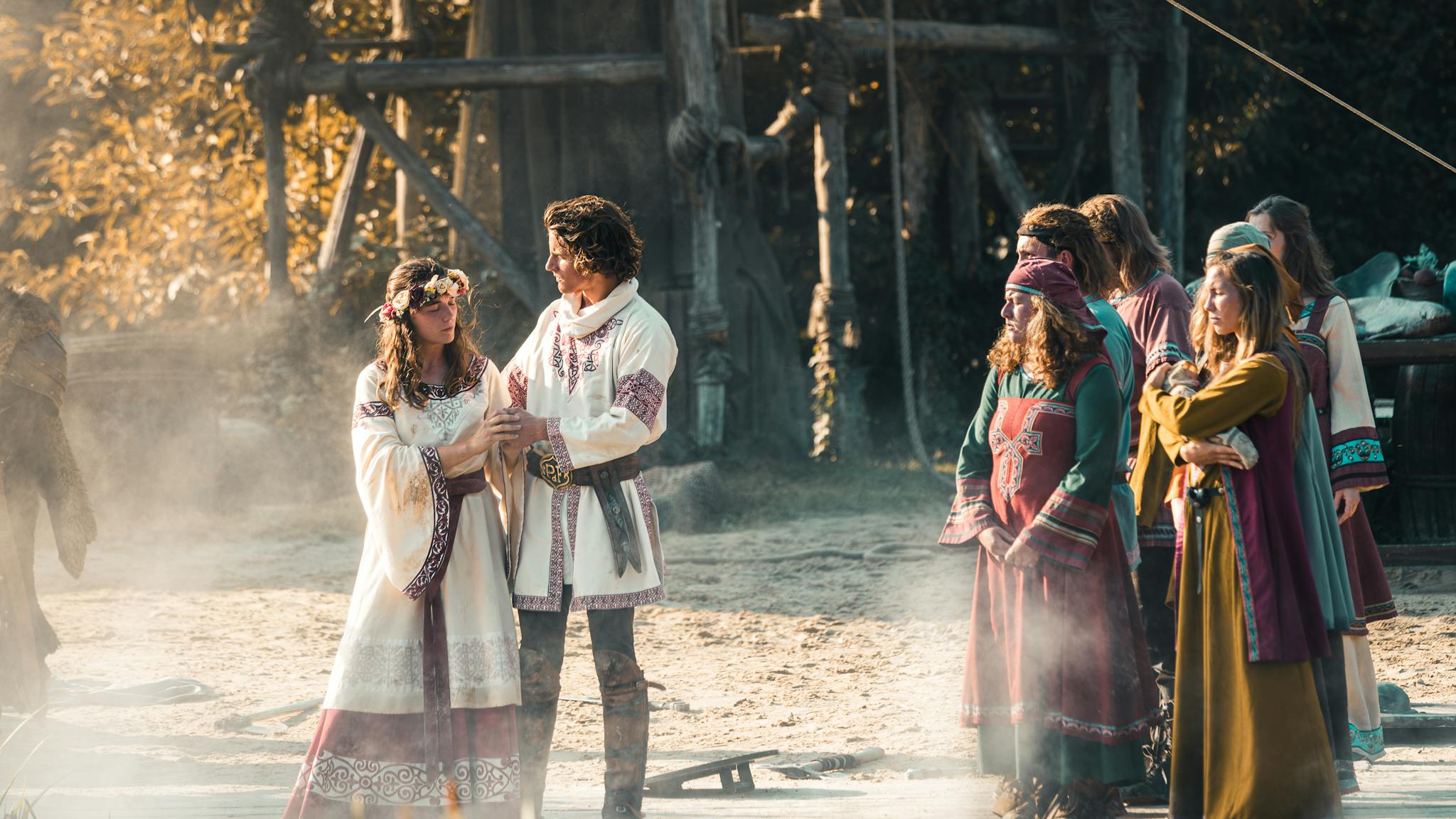 A group of people in medieval attire engaged in a reenactment outdoors.